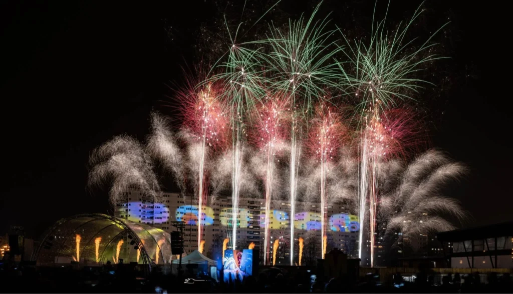 Gerbes pyrotechniques au-dessus d’une scène illuminée, devant le public