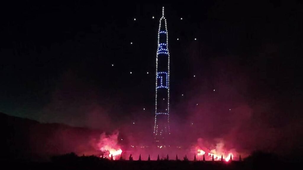 Drones lumineux dessinant une fusée dans le ciel nocturne
