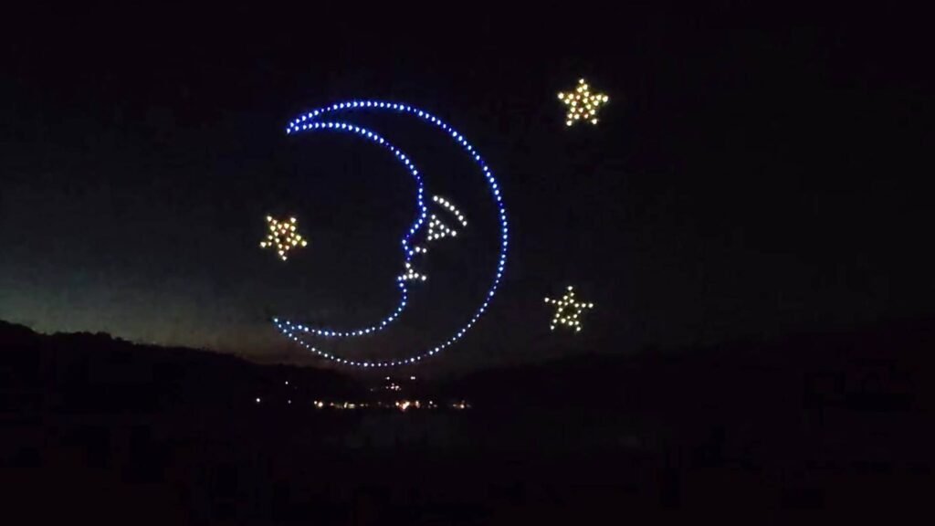 Drone lights drawing a moon and stars in the night sky