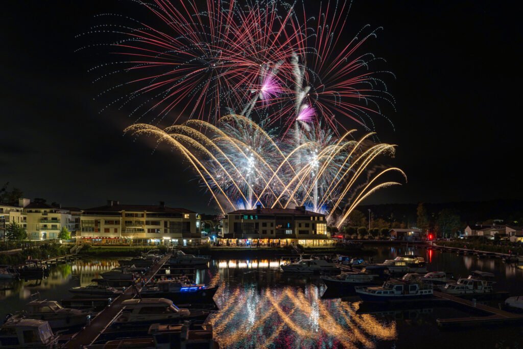 Éventails dorés et bombes rouges au-dessus de la Marina de L’Isle-Adam, reflétés dans le bassin du port